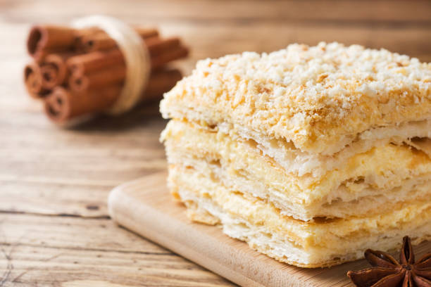 torta stratificata con crema napoleon millefeuille fetta di vaniglia con cannella e anice su sfondo legno. - tompouce foto e immagini stock