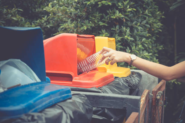 istock Young woman hand dropping plastic bottle into recycle bin. 1064870834