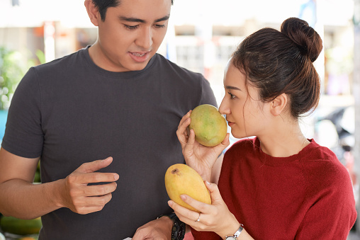 Young Vietnamese couple smelling mango and searching for ripe ones