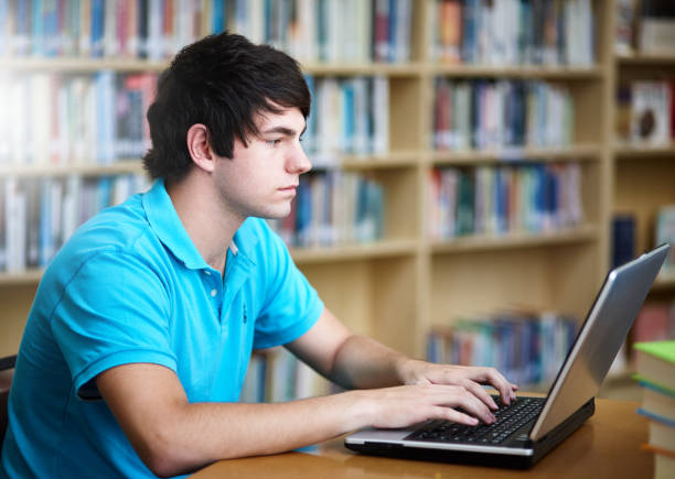 istock Male student working on laptop in library 1064875076