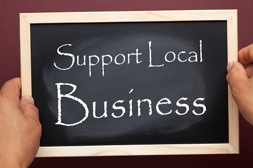 Hands holding blackboard with the text Support Local Business. Business concept.