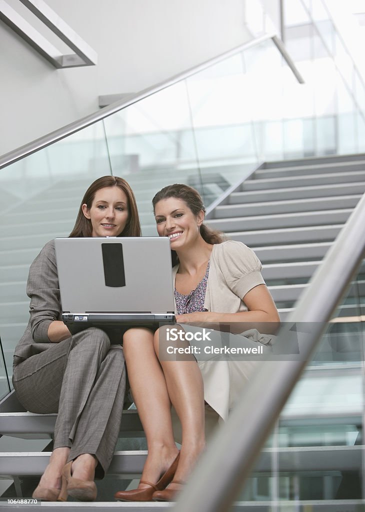 Deux femmes travaillant sur un ordinateur portable au bureau de l'escalier - Photo de 25-29 ans libre de droits