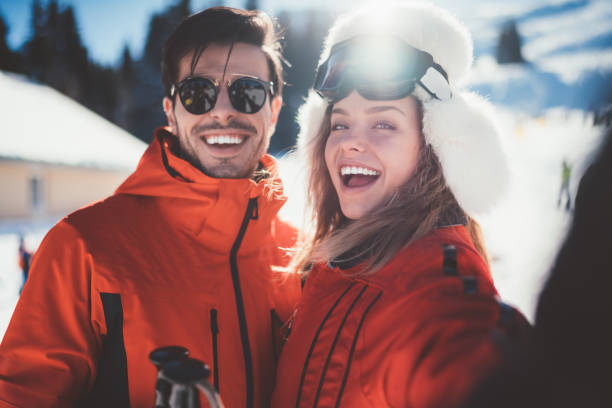 couple sur les vacances d’hiver en tenant selfie - ski winter women skiing photos et images de collection