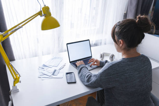 istock woman sitting at home working at laptop. white screen. 1064888552