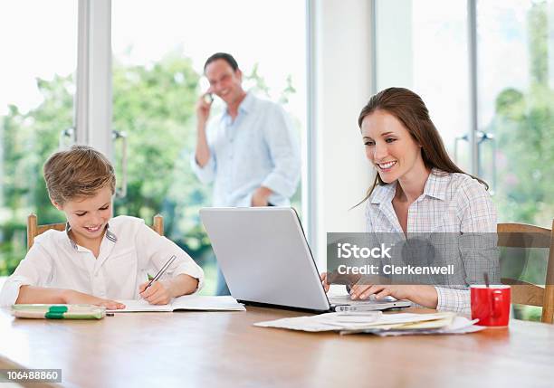 Madre Padre Utilizzando Un Computer Portatile Mentre Si Parla Al Telefono - Fotografie stock e altre immagini di 10-11 anni