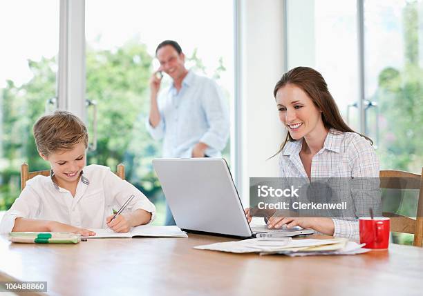 Foto de Mãe Usando O Laptop E Pais Falando No Telefone e mais fotos de stock de 10-11 Anos - 10-11 Anos, 30-34 Anos, 35-39 Anos