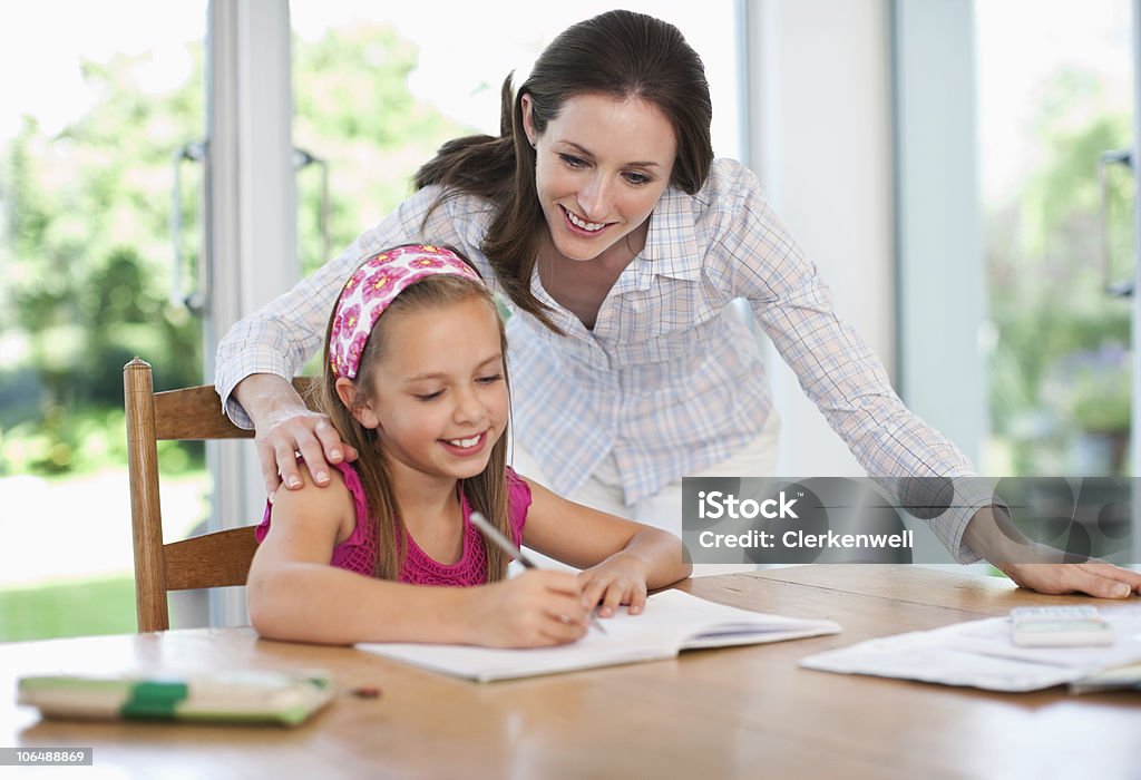 Madre aiutando Ragazza (8-9) con compiti di scuola - Foto stock royalty-free di 35-39 anni