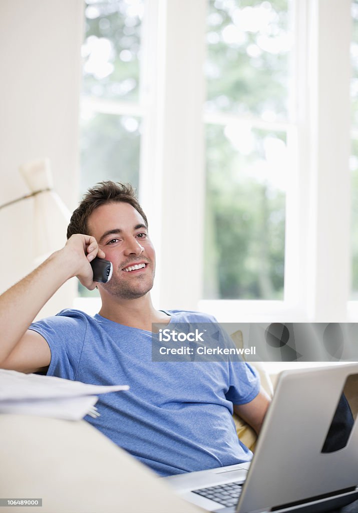 Sonriente hombre de mediana edad hablando por teléfono móvil mientras - Foto de stock de 30-34 años libre de derechos
