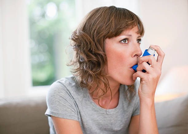 frau mittleren alters mit asthmainhalator - asthmainhalator stock-fotos und bilder