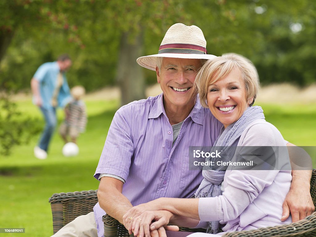 Pareja feliz en el jardín con personas en el fondo - Foto de stock de 30-34 años libre de derechos