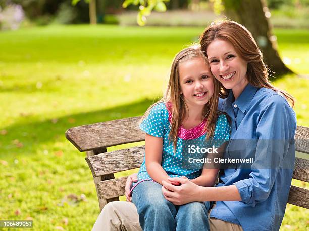 Sonriendo Madre Con Hija Sentado En El Banco En El Parque Foto de stock y más banco de imágenes de 35-39 años