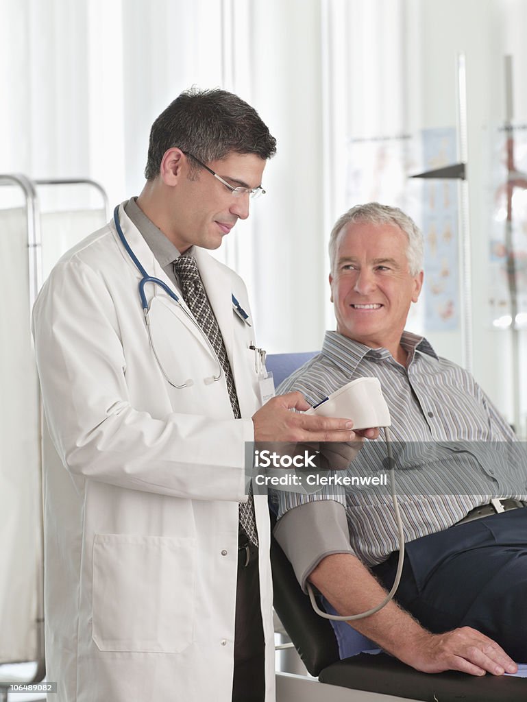 Médecin examine un patient la tension artérielle, souriant - Photo de Patient libre de droits