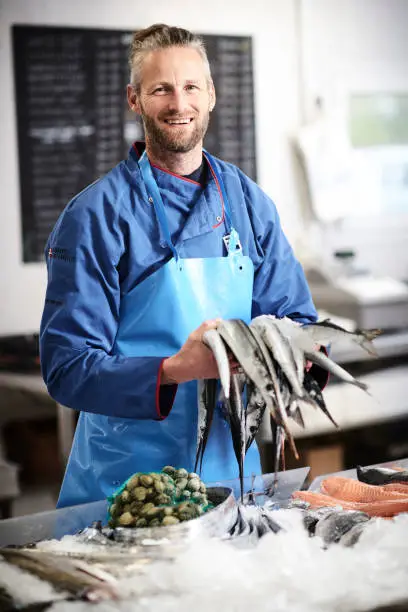 Young fisherman in his fishshop with fresh fish