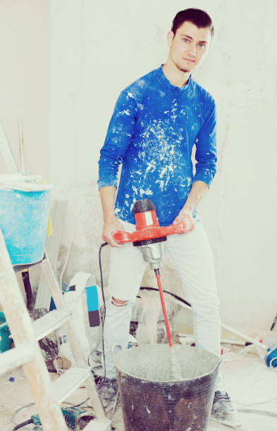 istock Male builder mixing plaster using electric mixer 1064900900