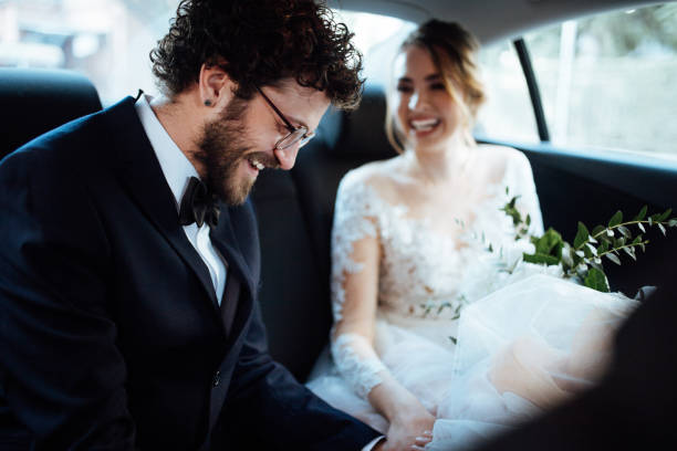 istock Newlyweds holding hands in the backseat 1064903394