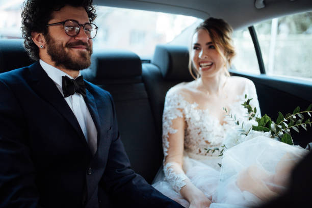istock Newlyweds holding hands in the backseat 1064903480