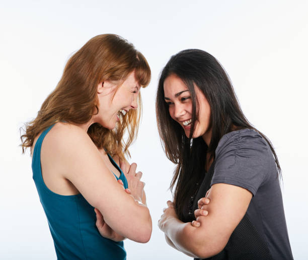 istock Two pretty women face each other, arms folded and laughing 1064903804