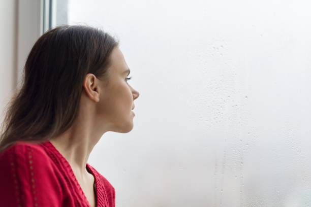 istock Young woman looking out the window on a rainy day, copy space 1064904180