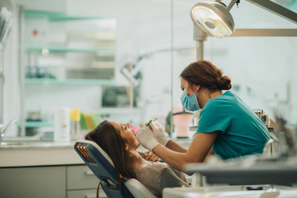 junge frau, die ihre zähne während der termin beim zahnarzt geprüft. - zahnarztpraxis stock-fotos und bilder