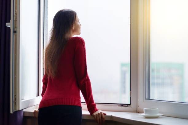istock Young woman opened a window enjoying the fresh air, side view 1064904976