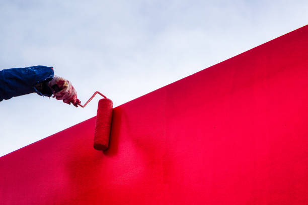 Red latex paint stucco wall Workers decorate the exterior wall to paint the city rose, the color is very comfortable, if you paint more than two times to ensure the color is dazzling house painter ladder paint men stock pictures, royalty-free photos & images