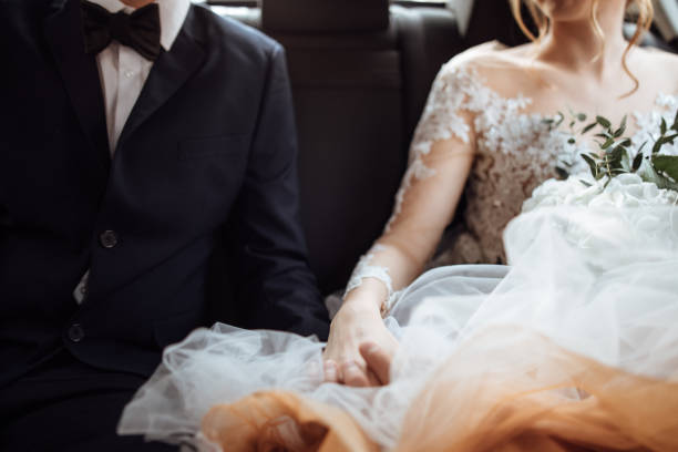 istock Newlyweds holding hands in the backseat 1064911612