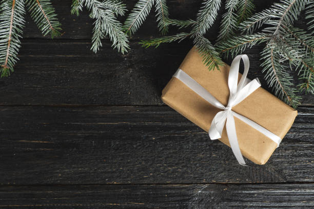 istock Gift box on a dark table with branches of a snow tree 1064917820