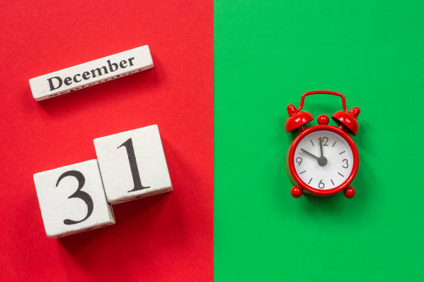 calendar December 31st and red alarm clock Wooden calendar December 31st and alarm clock on red and green background. Top view Flat lay Concept december 31 stock pictures, royalty-free photos & images