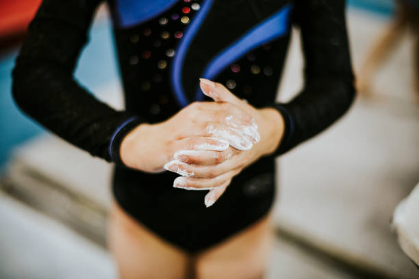 Young gymnast applying a powdered chalk to her palms