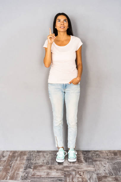 istock Happy curly woman having idea and showing forefinger while looking up over gray background. 1064924338