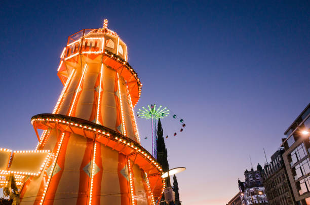 Edinburgh Christmas and New Year Attractions at Night Winter festival fairground attractions in Edinburgh, Scotland, part of Edinburgh's Christmas and Edinburgh's Hogmanay 2016. A brightly coloured helter-skelter, with high-rising Star Flyer swing ride in the background next to the Scott monument. hogmanay photos stock pictures, royalty-free photos & images