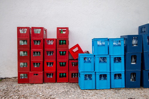 View of red and blue drink crates near a white wall.