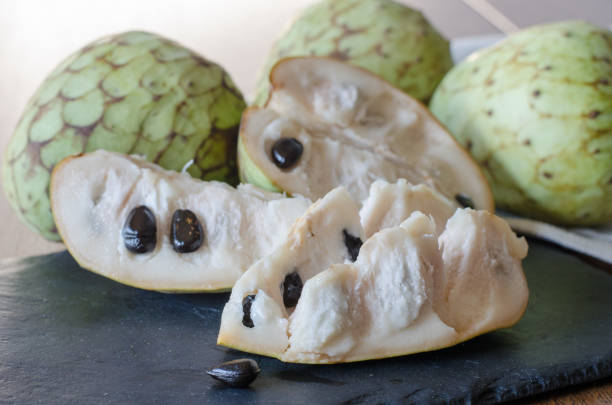 Sliced cherimoya on a black stone desk. Close up. Sliced cherimoya on a black stone desk. Close up. annonaceae stock pictures, royalty-free photos & images