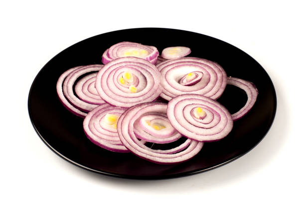 Sliced onions on a black plate. Isolated on white background. Selective focus