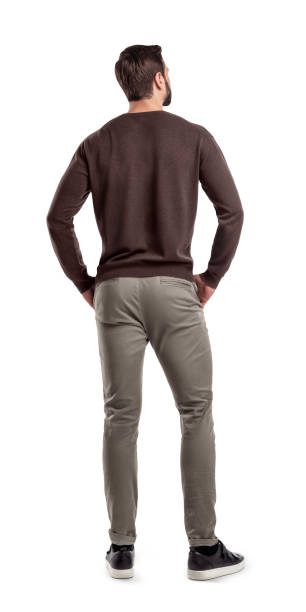 A back view on a modern fit and casually clothed man that stands in a relaxed posture and looks sideways. A back view on a modern fit and casually clothed man that stands in a relaxed posture and looks sideways. Man from back. Modern garb. Unrecognizable person. rezar stock pictures, royalty-free photos & images