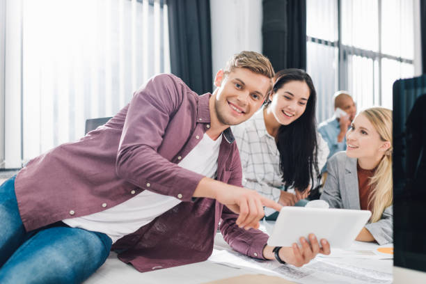 istock happy young business people using digital tablet and smiling in open space office 1064948458