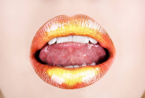 Full open mouth with naughty tongue and gold orange lipstick stock photo