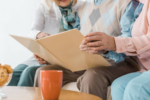 istock close up of senior people sitting on sofa and reading book 1064954942
