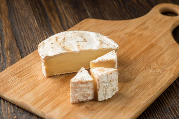 istock Brie cheese and tomato slice on wood cutting board. 1064966692