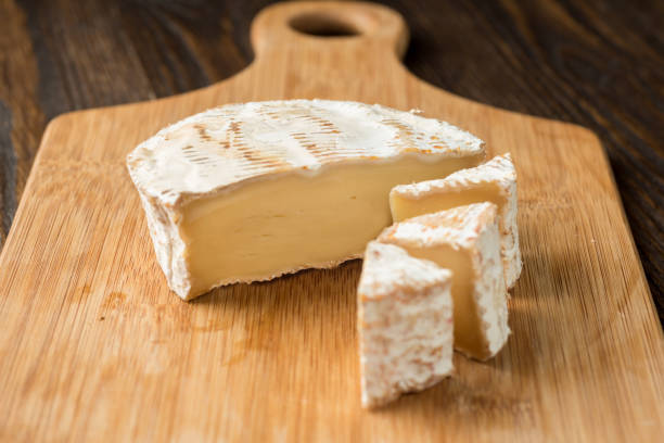 istock Brie cheese and tomato slice on wood cutting board. 1064966700
