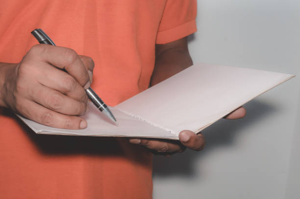 istock Writing with pen, notebook. African American Asian business man standing and working with documents in office, analyzing project report, financial strategic planning concept 1064970130