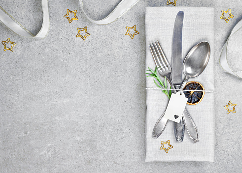 Christmas table setting background with copy space. Concrete background with napkin, silverware and rosemary branch. Cutlery with fork, knife and spoon. Top view, christmas decoration.