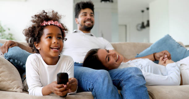 istock Young girl watching tv with her parents 1064970834