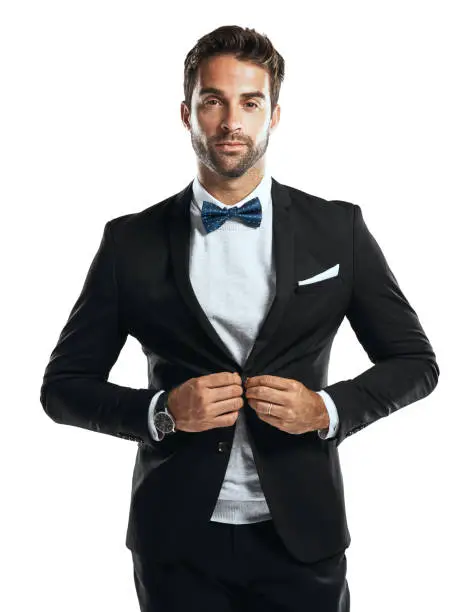 Studio shot of a handsome young man wearing a tuxedo against a white background