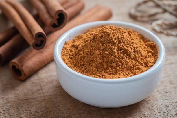 istock Cinnamon powder and cinnamon sticks on wooden table 1064978608