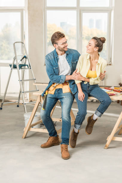 istock happy young couple hugging and smiling each other while sitting on table with tools 1064981710