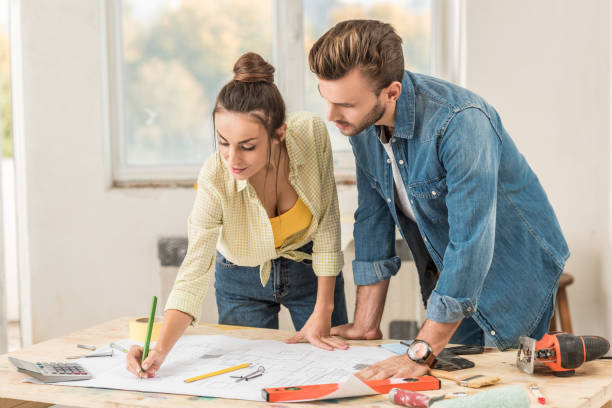 istock young couple marking blueprint and discussing renovation together 1064982156