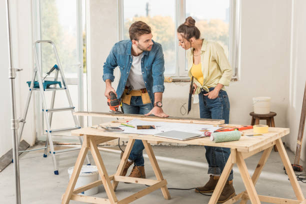 istock young woman looking at husband using electric jigsaw during repairment 1064982322