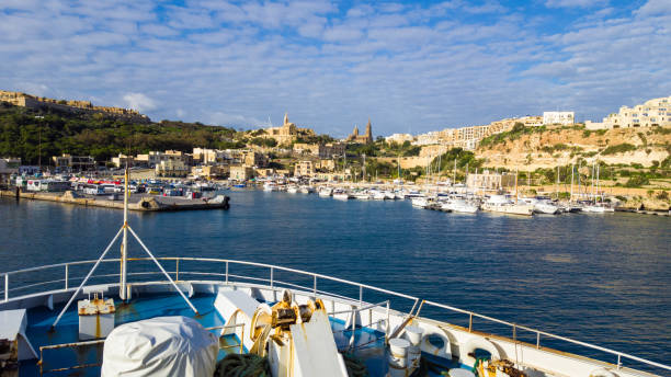 Ferry entrance into the harbor of Mgarr - Island Gozo, Malta Gozo, Malta - December 14, 2016 - Ferry entrance into the harbor of Mgarr - Island Gozo, Malta. People looking to the harbor mgarr malta island gozo cityscape with harbor stock pictures, royalty-free photos & images