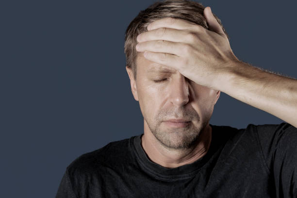istock A man holds his hands on his head on gray background. Headache and cold. 1064984878